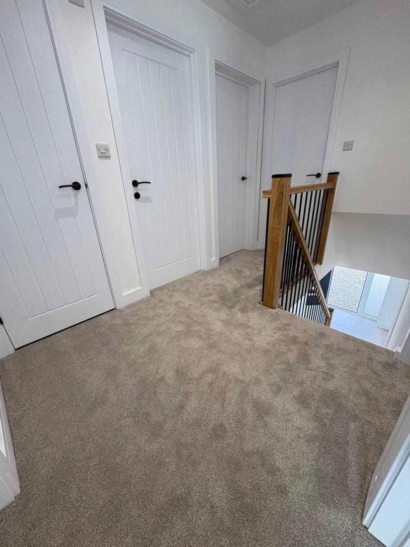 Landing with white doors and an oak banister with black spindles