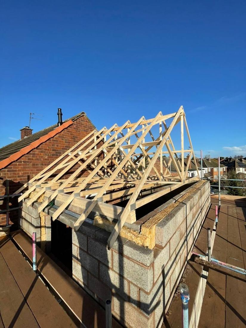 New trussed roof on a blockwork extension against a blue sky