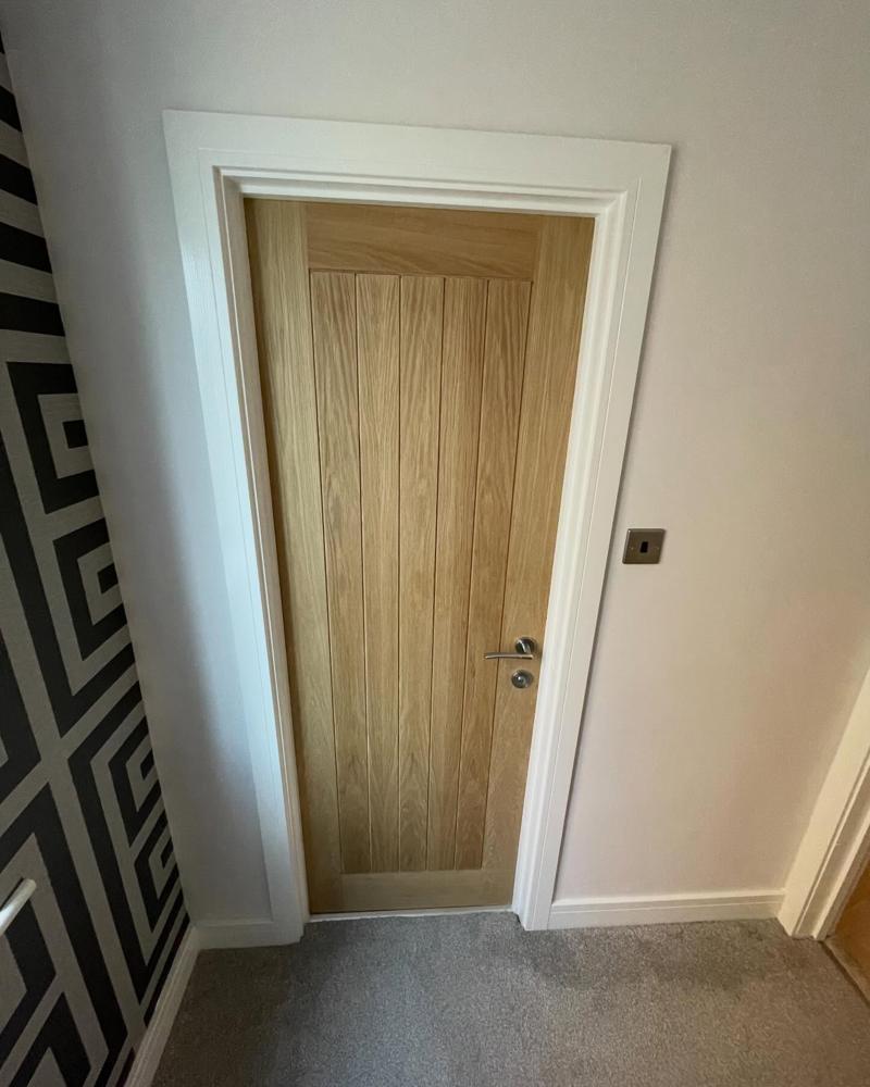 Holdenby oak door beside patterned wallpaper